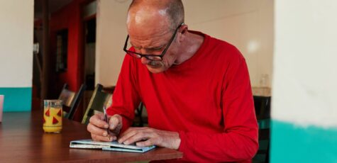 A man in a red crew neck jumper writing about the risks of pension drawdown.