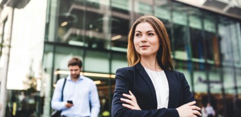 A woman in her 30s standing in front of an office block
